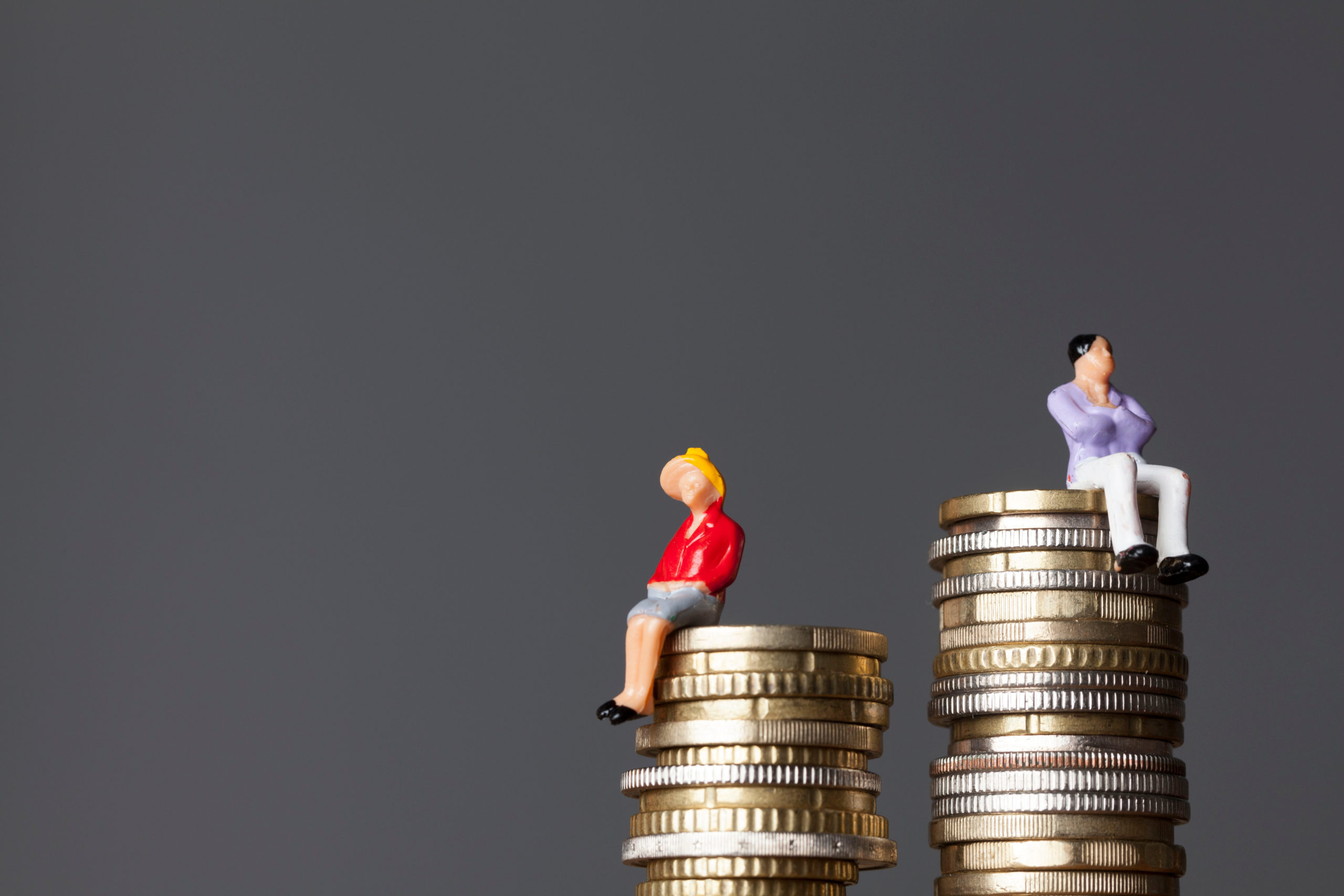 Egalité salariale : un homme et une femme sur des piles de pièces